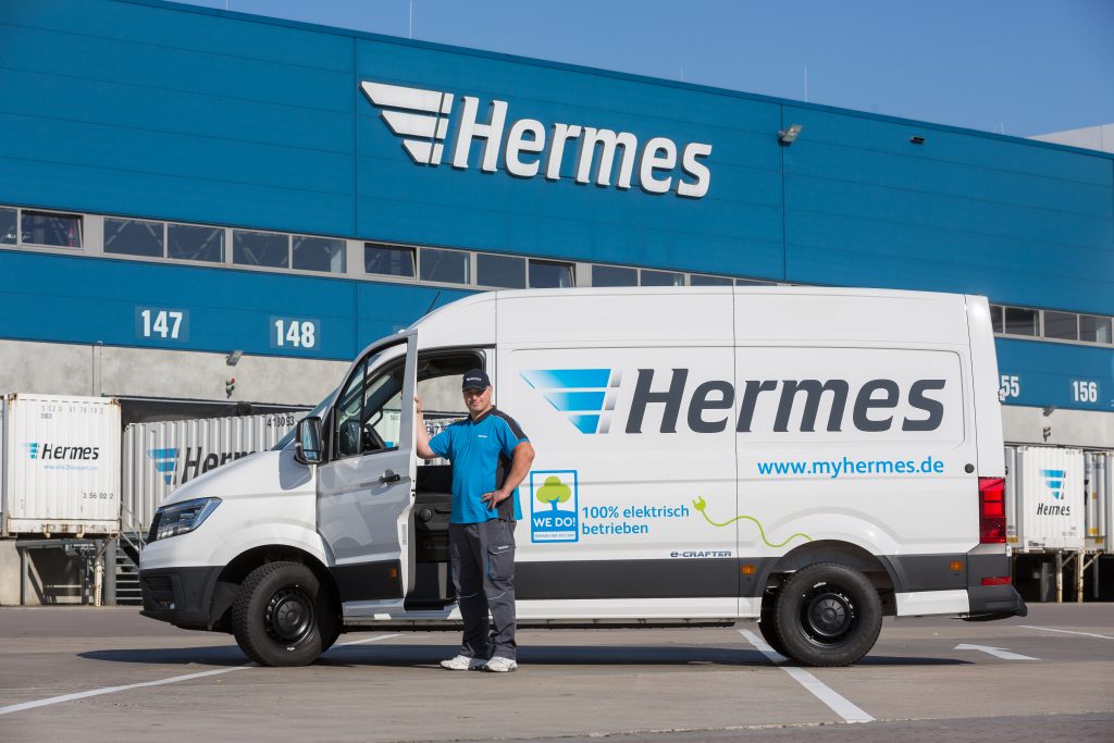 Ein Hermes Paketfahrer vor seinem Zustellfahrzeug